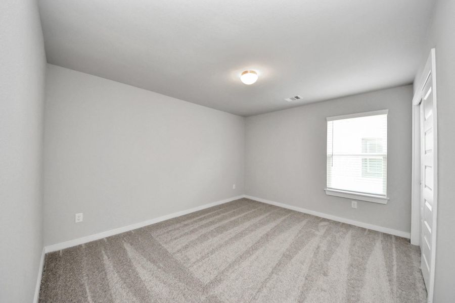 Secondary bedroom features plush carpeting, large windows that let in plenty of natural light, bright paint, and spacious closets. Sample photo of completed home with similar floor plan. Actual colors and selections may vary. Secondary bedroom features plush carpeting, large windows that let in plenty of natural light, bright paint, and spacious closets. Sample photo of completed home with similar floor plan. Actual colors and selections may vary.