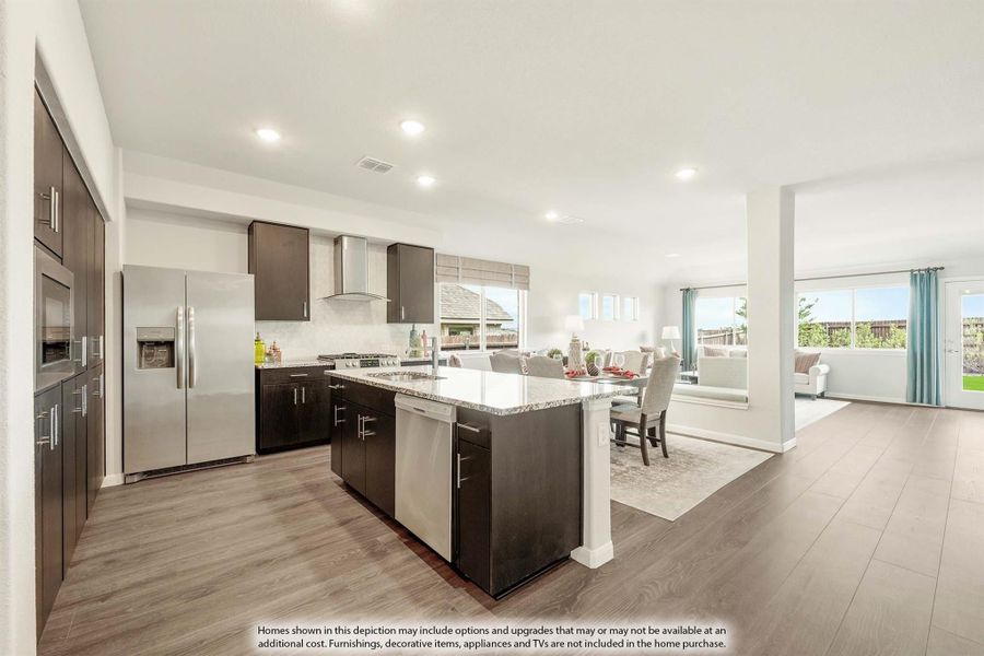 Open-concept kitchen with dark cabinets, granite island, stainless appliances, and wood floors flowing into dining and living areas Open-concept kitchen with dark cabinets, granite island, stainless appliances, and wood floors flowing into dining and living areas