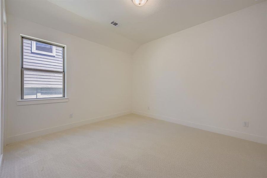 Spare room with vaulted ceiling and light colored carpet Spare room with vaulted ceiling and light colored carpet