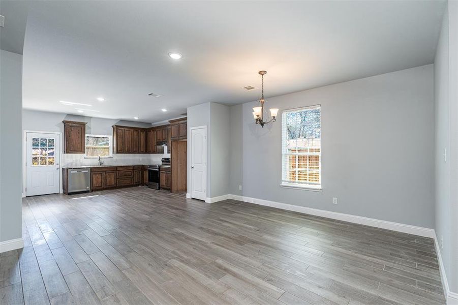 Kitchen with a wealth of natural light, light countertops, light wood-style flooring, an inviting chandelier, and appliances with stainless steel finishes