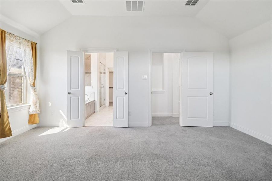 Unfurnished bedroom with lofted ceiling, light carpet, and ensuite bathroom Unfurnished bedroom with lofted ceiling, light carpet, and ensuite bathroom