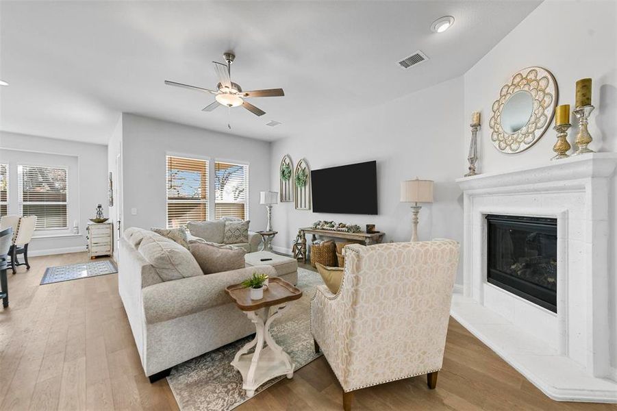 Living room with ceiling fan, light hardwood / wood-style flooring, and a tile fireplace