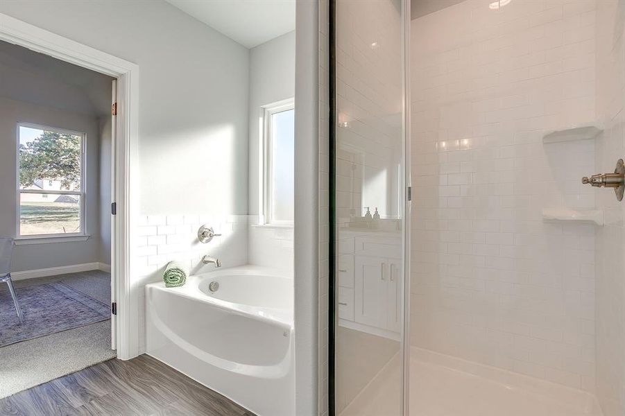 Bathroom featuring a garden tub, wood finished floors, and a shower stall