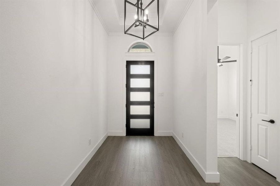 Foyer entrance featuring dark wood-style floors, a chandelier, ornamental molding, and ceiling fan