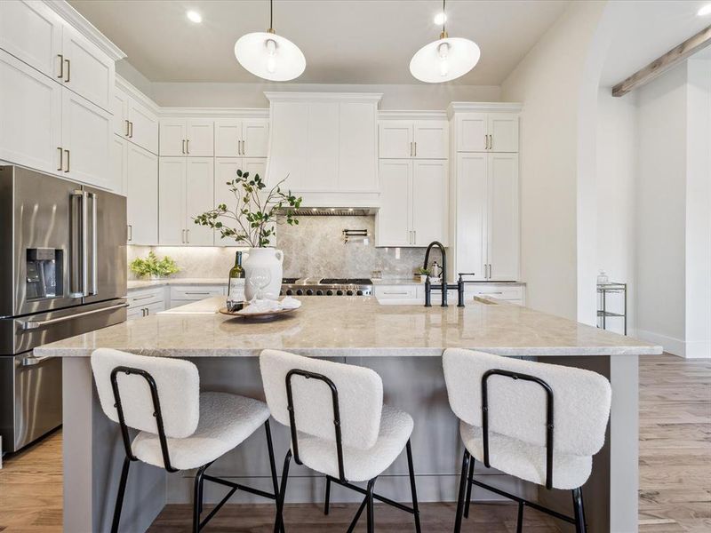 Kitchen featuring white cabinets, a kitchen island with sink, stainless steel appliances, and hanging light fixtures