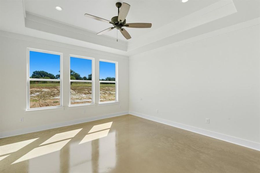 Spare room featuring a raised ceiling, concrete floors, a ceiling fan, and recessed lighting