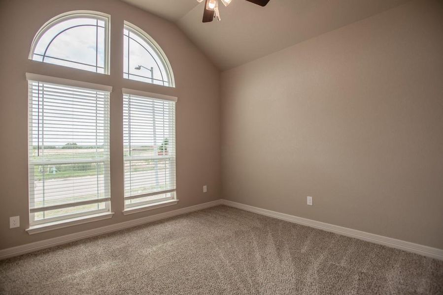 Empty room with ceiling fan, carpet, and vaulted ceiling Empty room with ceiling fan, carpet, and vaulted ceiling