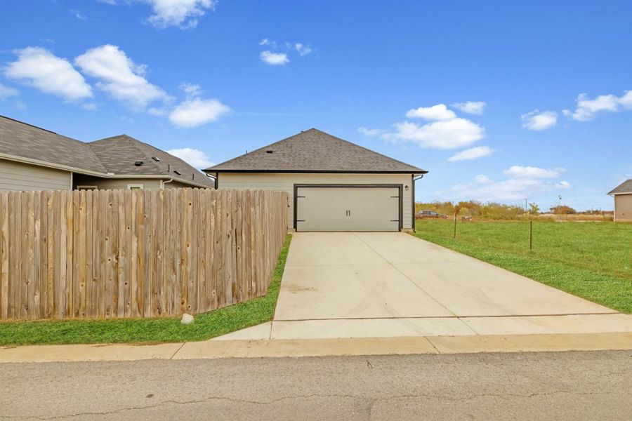 View of property exterior with a garage, concrete driveway, and roof with shingles