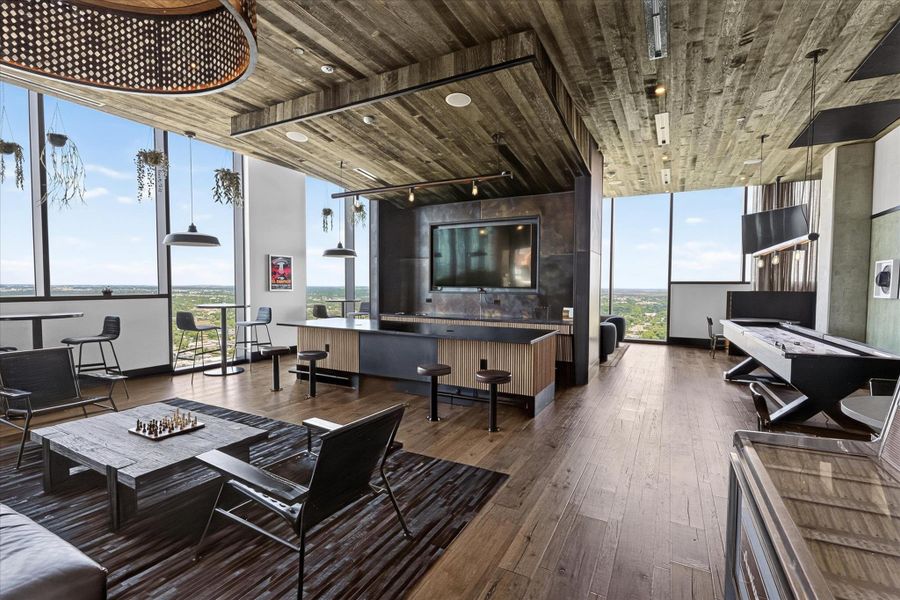 City views and natural light illuminate this entertainment space, featuring rich wood flooring and a distinctive ceiling design.