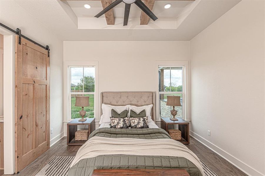 Bedroom with a barn door, a tray ceiling, wood finished floors, recessed lighting, and a ceiling fan