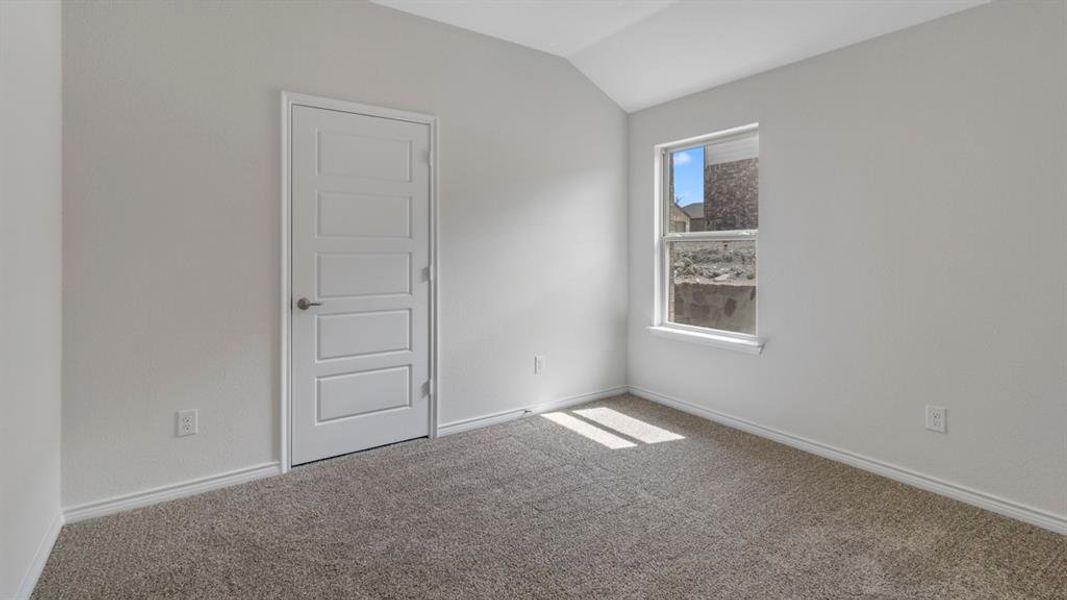 Carpeted spare room featuring baseboards and vaulted ceiling Carpeted spare room featuring baseboards and vaulted ceiling