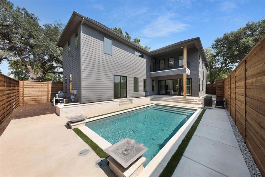 Back of property with a fenced backyard, a patio area, and a balcony