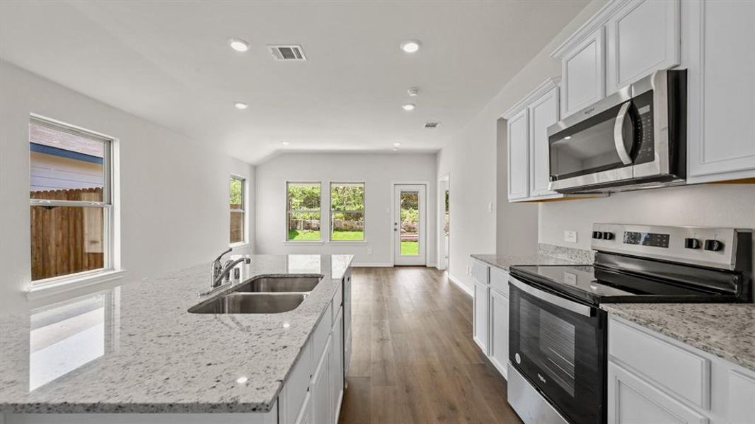 Kitchen featuring stainless steel appliances, white cabinetry, a dual basin sink, and ample countertop space