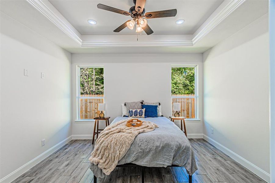 Bedroom featuring a tray ceiling, light wood finished floors, a ceiling fan, recessed lighting, and crown molding