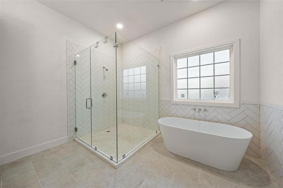 Full bath with a freestanding bath, a stall shower, tile patterned flooring, and tile walls Full bath with a freestanding bath, a stall shower, tile patterned flooring, and tile walls