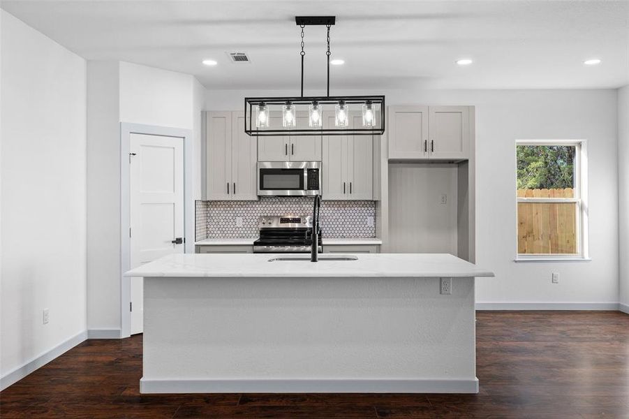 Kitchen featuring hanging light fixtures, decorative backsplash, stainless steel appliances, dark wood-type flooring, and recessed lighting
