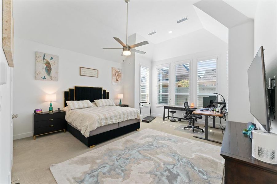 This room features a high vaulted ceiling, light-colored carpeting, and a ceiling fan with a light fixture