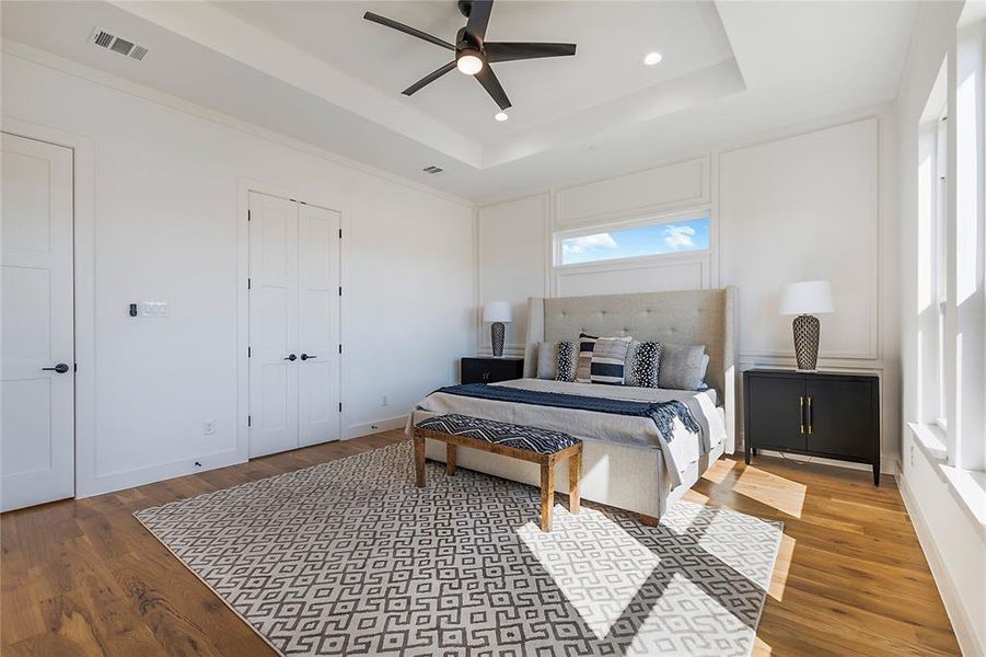 Bedroom featuring wood-type flooring, a tray ceiling, and ceiling fan