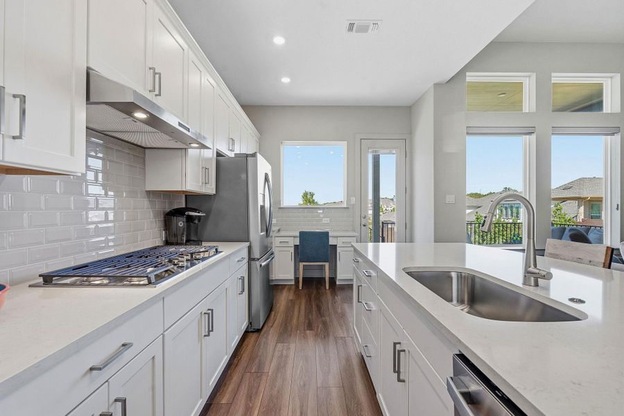 Kitchen featuring white cabinetry, light stone counters, dark wood finished floors, stainless steel appliances, and recessed lighting Kitchen featuring white cabinetry, light stone counters, dark wood finished floors, stainless steel appliances, and recessed lighting