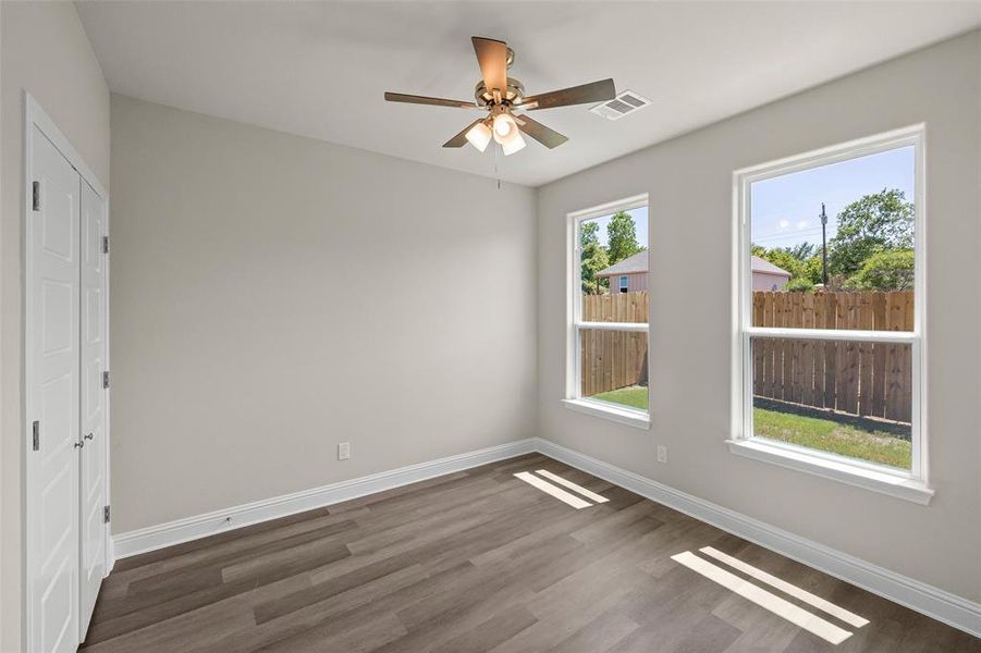 Bedroom with dark wood-type flooring, ceiling fan, and a healthy amount of sunlight