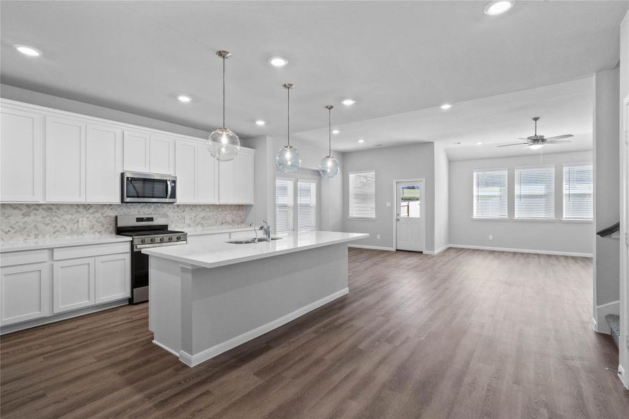 As you step past the entryway, you are immediately welcomed by a bright, open-concept kitchen that serves as the home's focal point. The space feels clean and modern, anchored by a large quartz-topped island that seamlessly connects the cooking area to a long, light-filled living space.