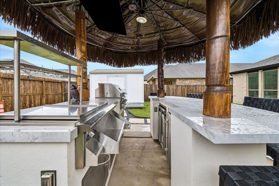 This backyard offers a rare opportunity to build on what’s already here and create the outdoor retreat you’ve been dreaming of. The tiki bar will be removed, but the base pad, electrical wiring & plumbing will stay, leaving the next owner ready to design a custom summer kitchen, outdoor lounge, expanded entertaining space or something entirely their own. This setup was designed and purchased through Paradise Grills.