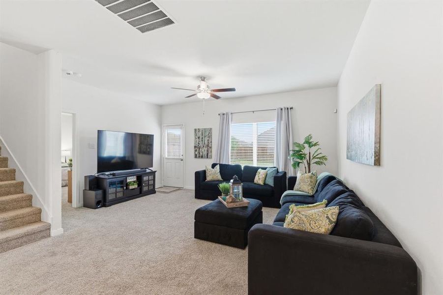 The property features a spacious living room with neutral-toned carpeting, a ceiling fan, and large windows providing natural light