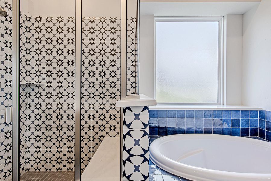 The walk-in shower showcases striking geometric tilework that adds bold character, perfectly complemented by a generously sized soaking tub wrapped in rich indigo tile.