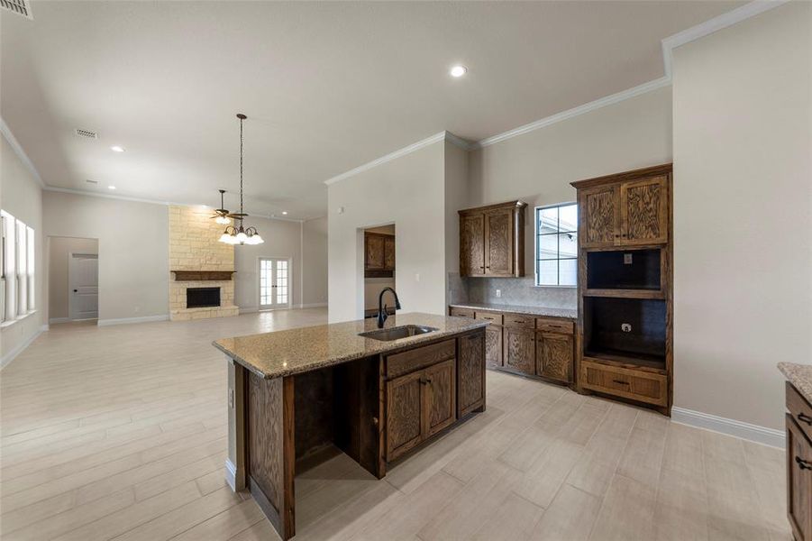 Kitchen with light stone countertops, sink, an island with sink, and a healthy amount of sunlight