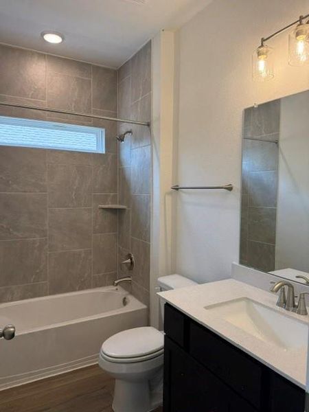 Contemporary bathroom featuring large format gray wall tile, a built-in tub with a shower fixture, and a horizontal window