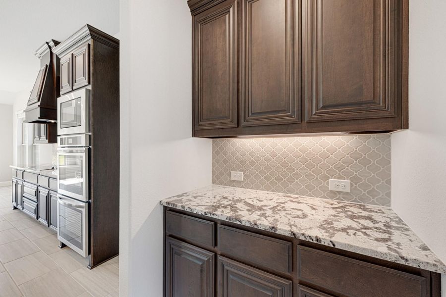 Kitchen with dark wood cabinets, granite countertops, arabesque tile backsplash, and stainless steel appliances in background Kitchen with dark wood cabinets, granite countertops, arabesque tile backsplash, and stainless steel appliances in background