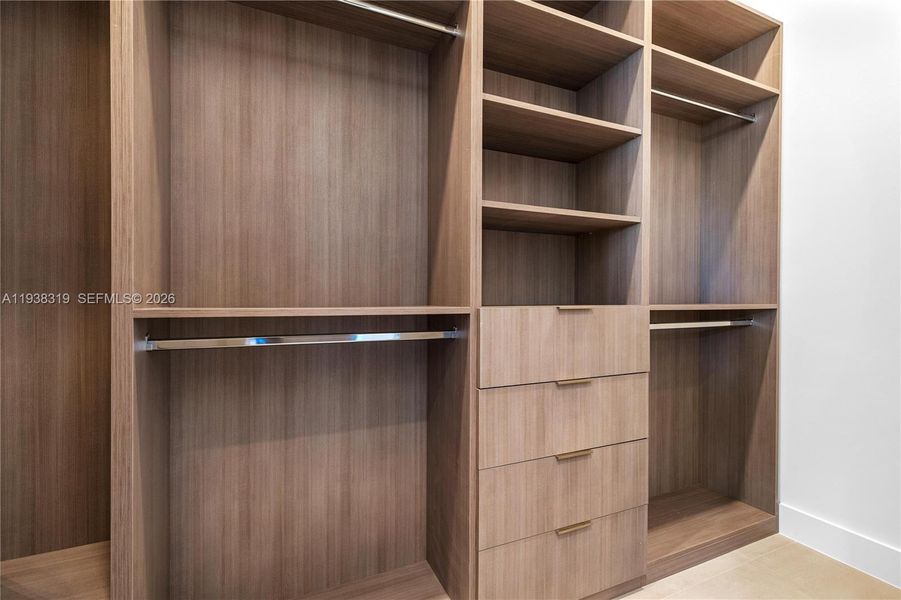 The primary suite includes his-and-hers closets with custom-built cabinetry, providing ample organized storage and a luxurious touch.