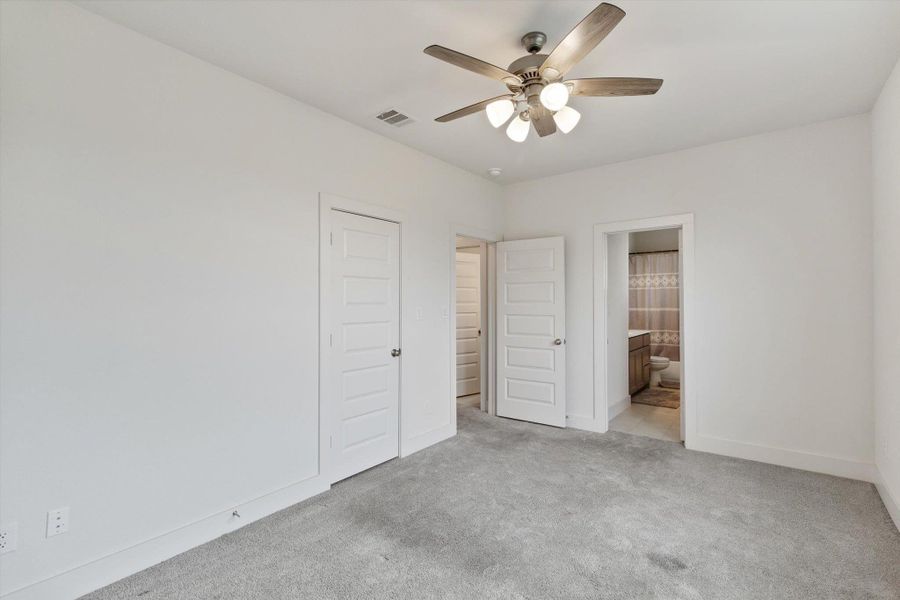 Unfurnished bedroom with carpet floors, ceiling fan, and ensuite bathroom