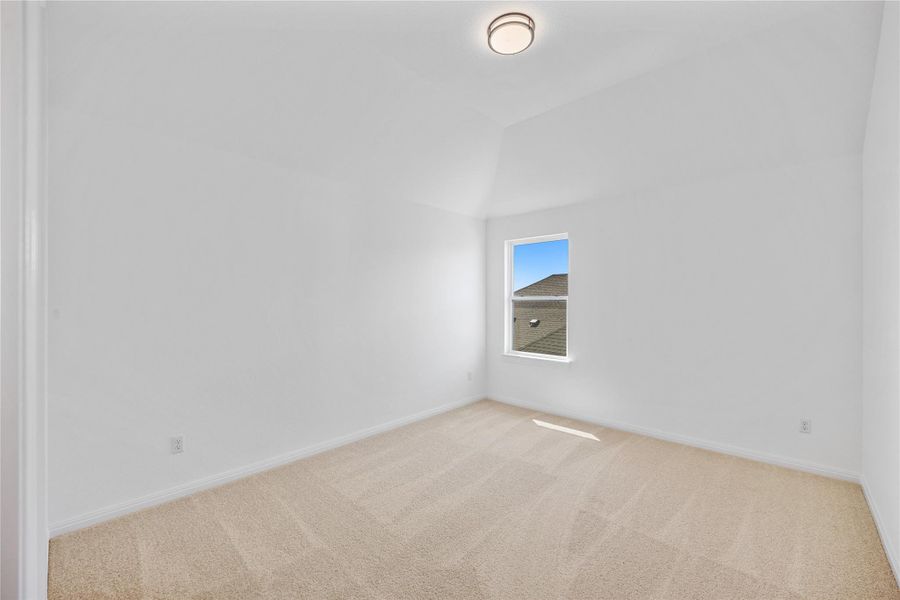 Carpeted empty room featuring baseboards and vaulted ceiling