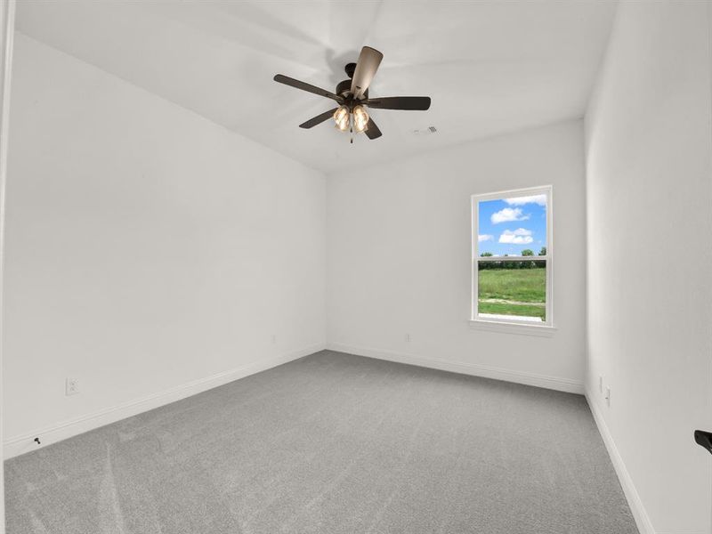 Carpeted spare room featuring ceiling fan and baseboards