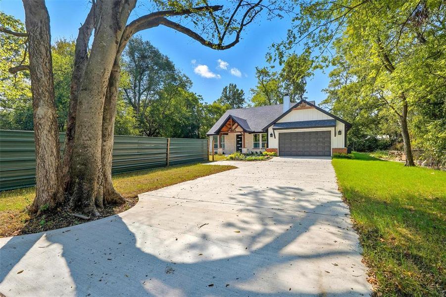 View of front of property featuring concrete driveway, a chimney, board and batten siding, and an attached garage View of front of property featuring concrete driveway, a chimney, board and batten siding, and an attached garage