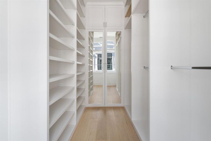 The spacious walk-in closet features elevated features such as furniture style cabinetry, adjustable shelves, a vanity area with specialized accessory storage, valet rods, and more (photo of interior model home with smaller floor plan)