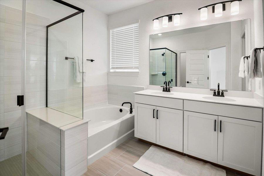 A well-appointed bathroom offers a glass-enclosed shower, a relaxing soaking tub, and a dual vanity with a wide mirror.