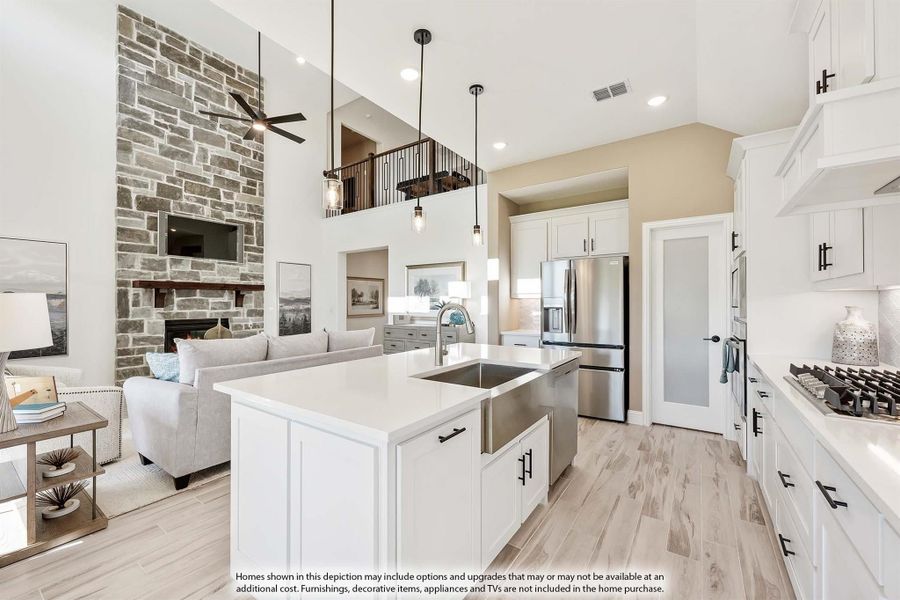Open-concept kitchen with white island, quartz counters, and stone fireplace visible in adjoining living room Open-concept kitchen with white island, quartz counters, and stone fireplace visible in adjoining living room