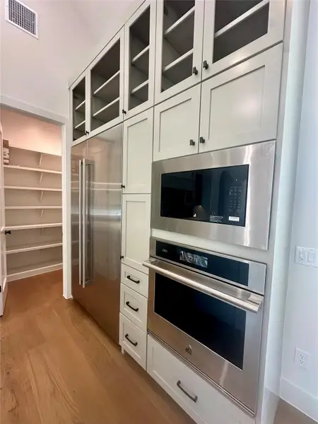 Floor-to-ceiling cabinetry integrates stainless steel appliances alongside warm hardwood flooring.