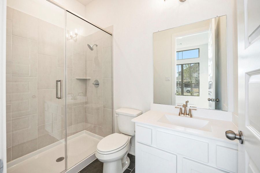 The secondary bathroom features a modern walk-in shower with elegant tile finishes and refined fixtures. Designed for both style and convenience, this beautifully appointed space offers a perfect blend of luxury and practicality for guests or family members.