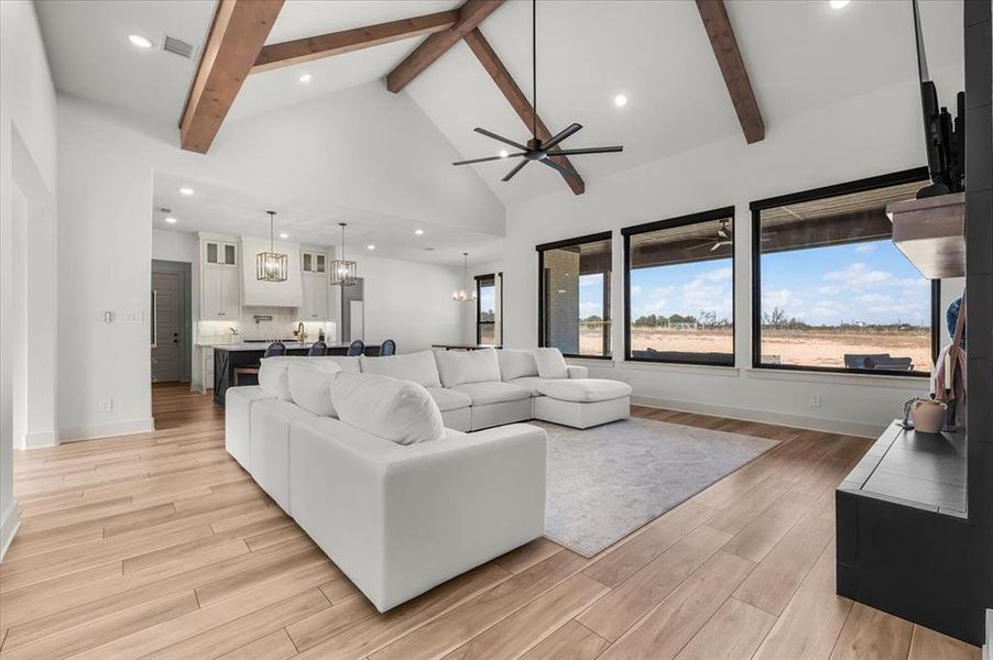 Living room featuring beamed ceiling, ceiling fan, and high vaulted ceiling