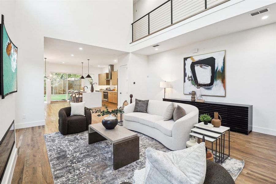 Living room featuring a towering ceiling, wood-type flooring, and sink