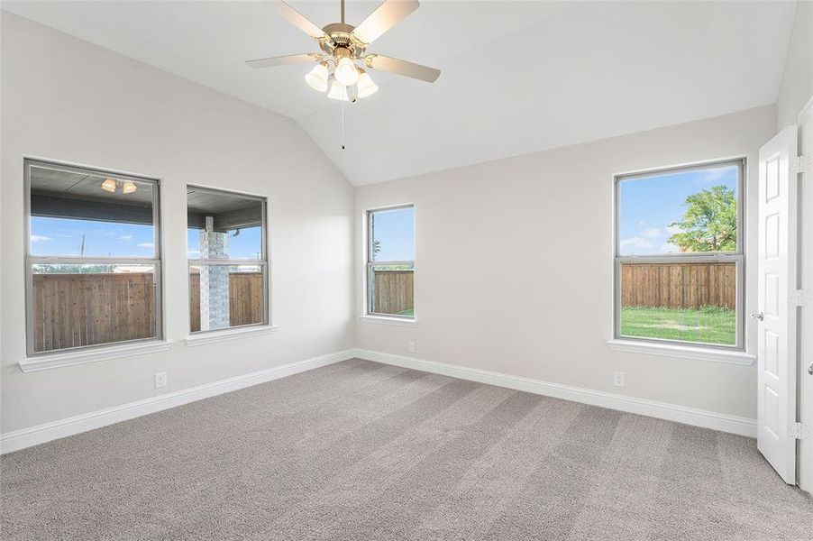 Empty room with lofted ceiling, light carpet, plenty of natural light, and ceiling fan Empty room with lofted ceiling, light carpet, plenty of natural light, and ceiling fan