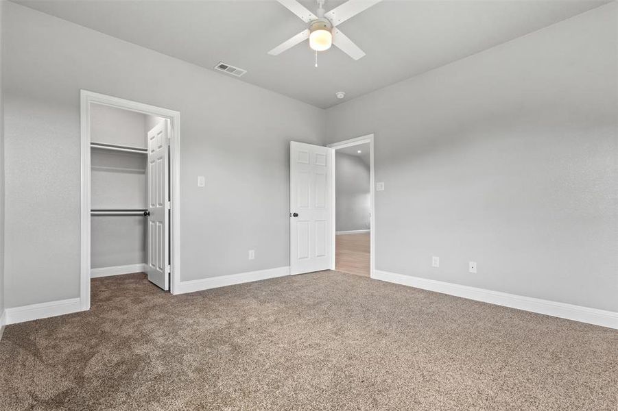 Unfurnished bedroom #4 with carpet, a walk in closet, and a ceiling fan with Jack & Jill bathroom