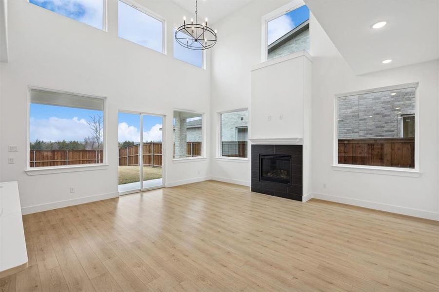 Unfurnished living room featuring a notable chandelier, light hardwood / wood-style floors, and a high ceiling