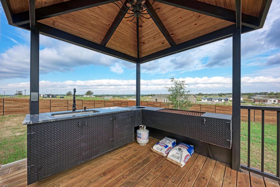 A cedar-lined pavilion shelters a fully equipped outdoor kitchen on a spacious wooden deck. A cedar-lined pavilion shelters a fully equipped outdoor kitchen on a spacious wooden deck.