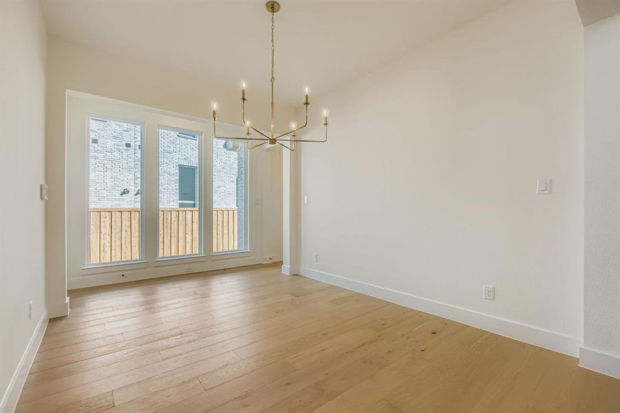 Unfurnished dining area featuring light wood-type flooring and a chandelier