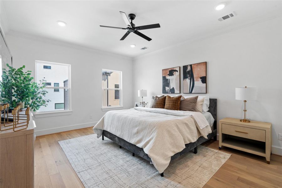 A bright and airy primary bedroom highlighted by designer touches, white oak flooring, and a serene ambiance ideal for unwinding in style.