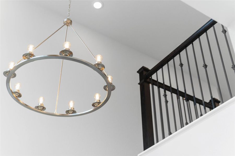 A stunning, generously sized 12-light wagon wheel-style chandelier with a sophisticated brushed nickel finish. This modern transitional fixture provides a strong focal point in the entryway, offering abundant ambient light to the high-ceilinged space. The exposed, candle-style bulbs complement the sleek, open-ring design and create a warm, inviting glow.